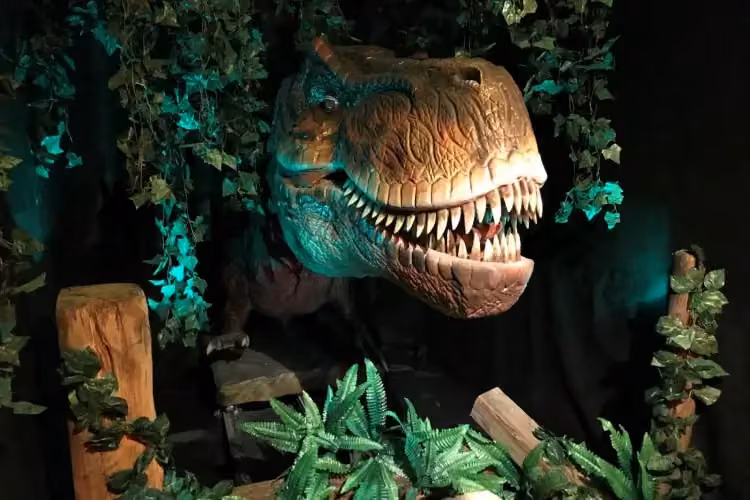 Dinosaurier-Attraktion in Tirol – T-Rex-Kopf in einer Dschungelkulisse mit Lichteffekten. Perfekt für einen spannenden Ausflug mit Kindern in Tirol.