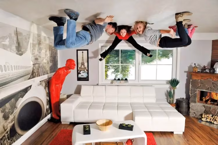 Eine Familie posiert kopfüber in einem Wohnzimmer des Upside-Down-Hauses im Tirolland – eine verrückte Indoor Aktivität in Tirol.