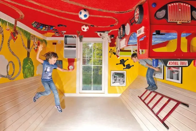 Zwei Kinder toben in einem bunten, auf dem Kopf stehenden Kinderzimmer – ein spannendes Erlebnis beim Ausflug in Tirol im Tirolland.