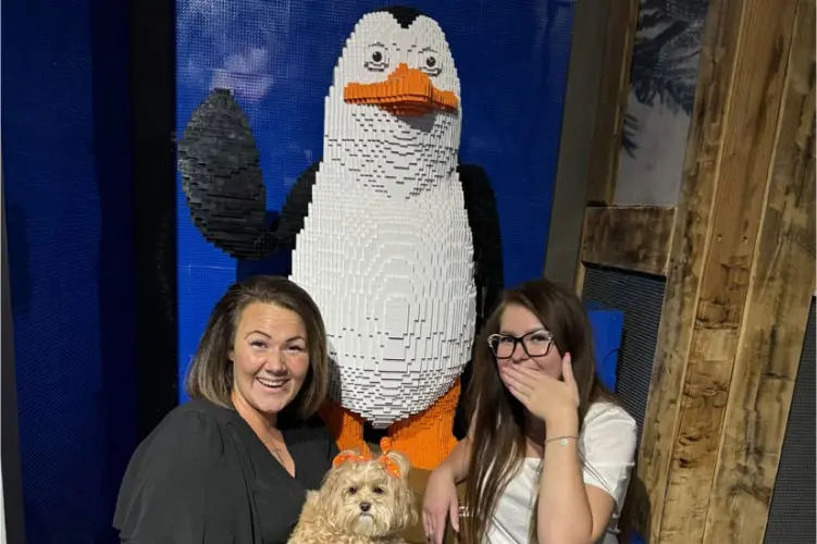 Zwei lachende Frauen posieren mit einer riesigen LEGO-Pinguin-Figur im Tirolland – ein unterhaltsames Erlebnis für die ganze Familie beim Ausflug in Tirol.