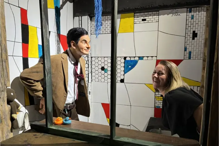 Eine Frau interagiert lachend mit der Wachsfigur von Mr. Bean im Tirolland – ein humorvolles Highlight beim Ausflug in Tirol.